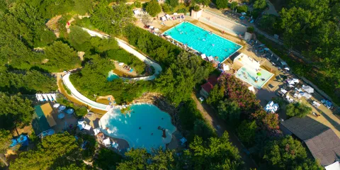 Aerial view of a lush water park with pools and slides surrounded by trees.