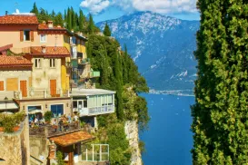 Hilltop houses overlooking a blue lake with mountains in the background.