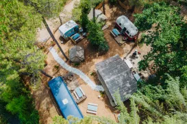 Aerial view of a campsite with trailers and picnic tables among trees.