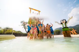 Children playing in a water park, splashing under a large bucket.
