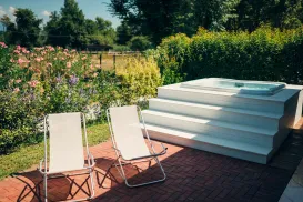 Two lounge chairs and a jacuzzi in a garden with flowers.