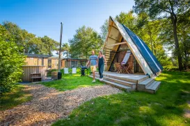 A-frame cabin in a sunny, wooded campsite.