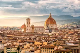 Florence skyline with the Duomo at sunset, under a cloudy sky.
