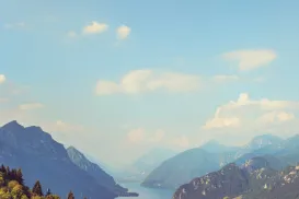 Mountainous landscape with a lake, village, and clear blue sky.