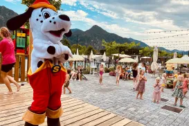 Spotty in red pants on stage, mountains and crowd in background.