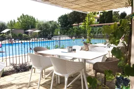 Outdoor patio with white chairs, table, and pool view.