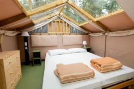 Cozy tent bedroom with skylight, bed, and folded towels.