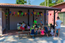 Children sitting and playing under a pavilion with colorful flags.