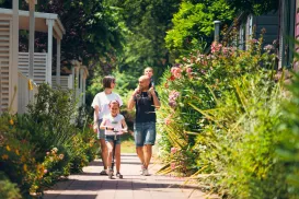 Family walking on a sunny path lined with lush greenery and flowers.