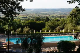 Swimming pool surrounded by trees, with hills in the distance.