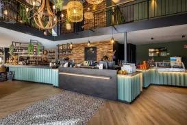 Cozy cafe with rustic decor, warm lighting, and a central counter with green accents.