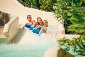 Family joyfully descending a water slide.