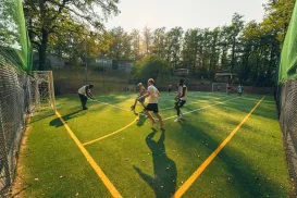 Players enjoy a game of soccer on a sunny, tree-lined field.