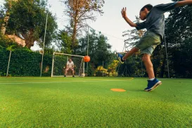 Boy kicking soccer ball towards goalie on outdoor field.