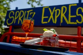 A refreshing drink and dessert on a table outside with a "Spritz Express" sign.