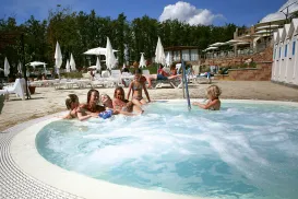 People relaxing in a jacuzzi at a sunny outdoor resort with umbrellas.
