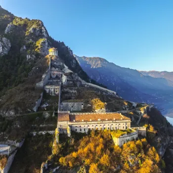 Aerial view of a mountain fortress, bathed in golden sunlight.