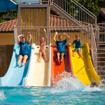 Kids sliding down colorful waterslides into a pool.
