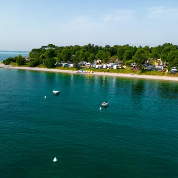 Coastal campsite with calm waters and several anchored boats.