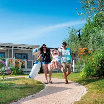 Family walking along a garden path under a clear blue sky.