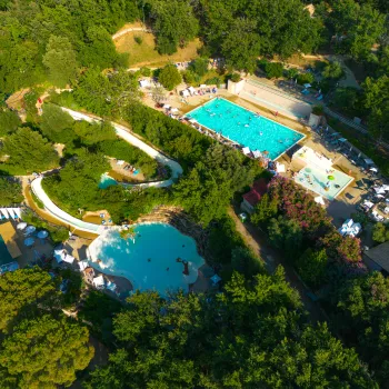 Aerial view of a lush water park with pools and slides surrounded by trees.