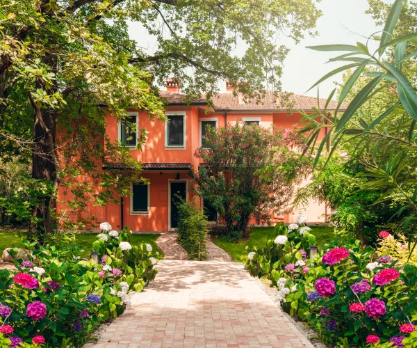 Two-story house with pink flowers and lush green garden.