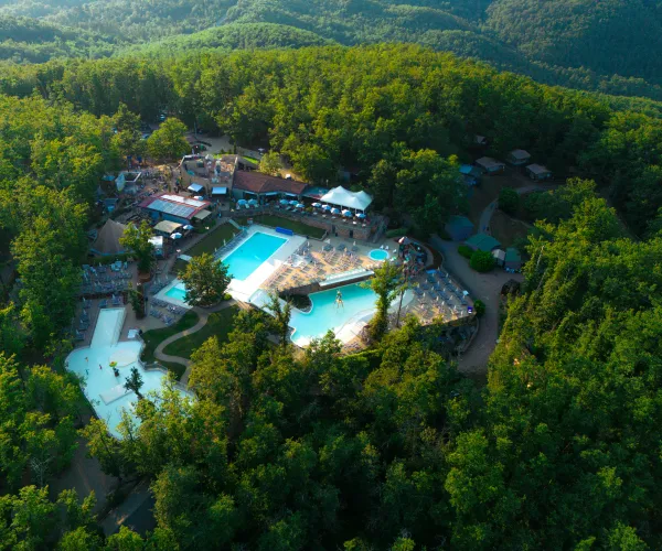 Aerial view of a forest-surrounded water park with pools and slides.