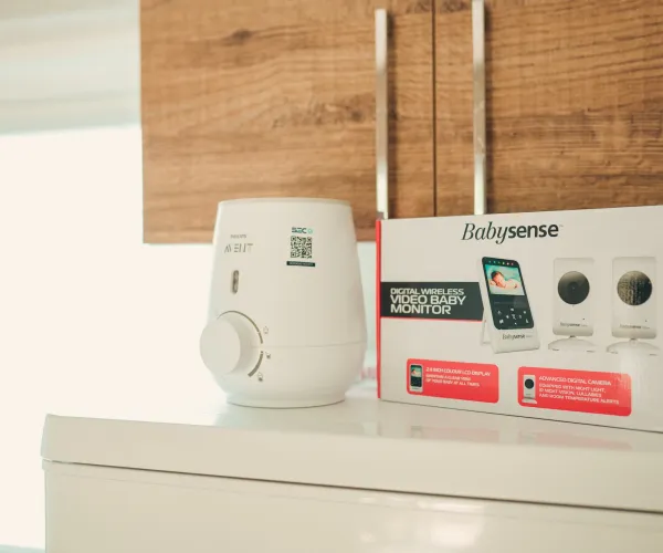 Thermostat and packaging on a white table under a wooden cabinet.