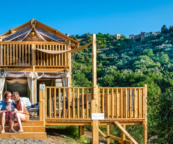 Air lodge with people seated, set against a green hillside under a blue sky.