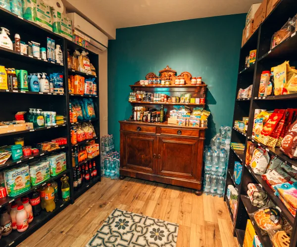 Pantry with wooden shelves stocked with various groceries and bottled drinks.
