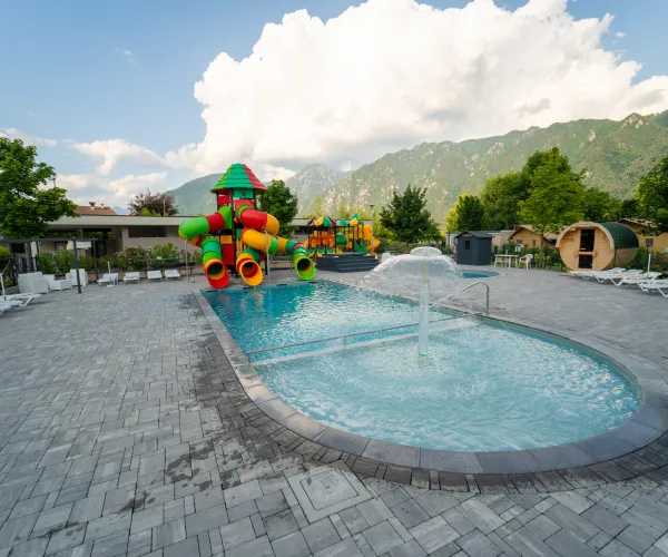 Children's pool with colorful slides, mountains in the background.