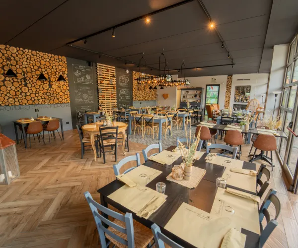 Modern restaurant interior with wooden tables, chairs, and decorative logs.