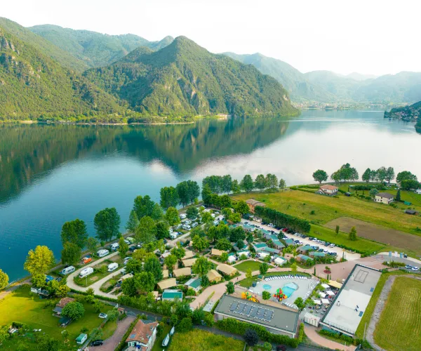 Aerial view of lakeside campsite with mountains in the background.