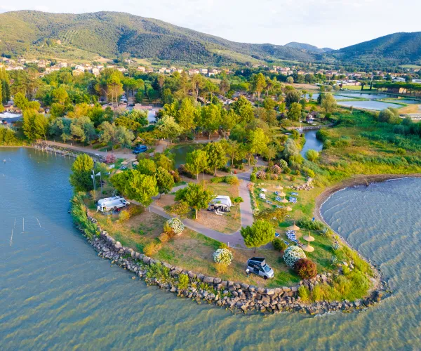 Aerial view of a lush peninsula with trees surrounded by water and distant hills.