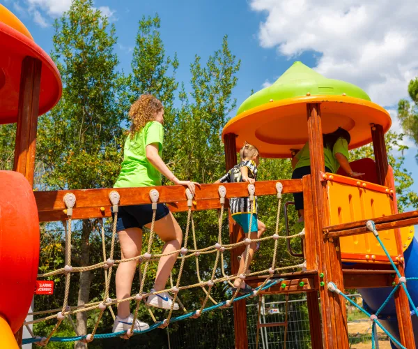 Children playing on a colorful playground structure under a sunny sky.