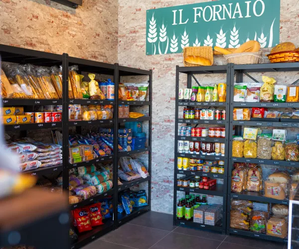 Grocery store shelves with packaged goods and a sign reading "Il Fornaio".