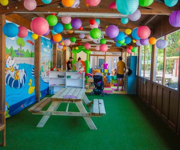Colorful indoor play area with hanging balloons and a picnic table.