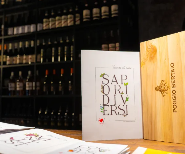 A wine cellar with bottles, a brochure, and a wooden box on a table.