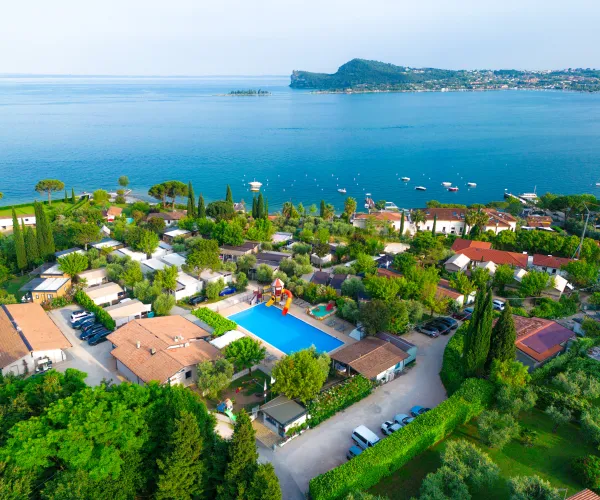 Coastal view of villas with a pool, surrounded by greenery and water.