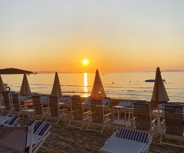 Sunset over a beach with loungers and umbrellas.
