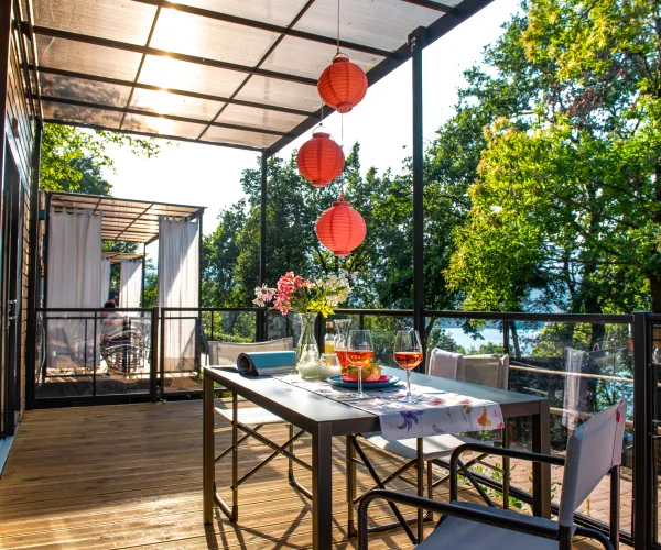Outdoor patio with a table set for two, surrounded by trees and red lanterns.