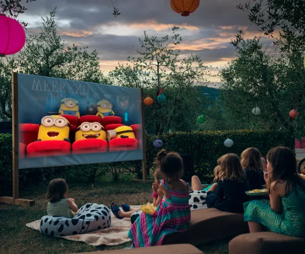 Outdoor movie night with kids watching an animated film at sunset.