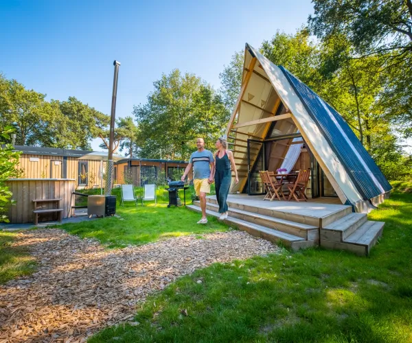 A-frame cabin in a sunny, wooded campsite.