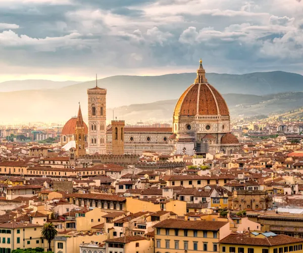 Florence skyline with the Duomo at sunset, under a cloudy sky.