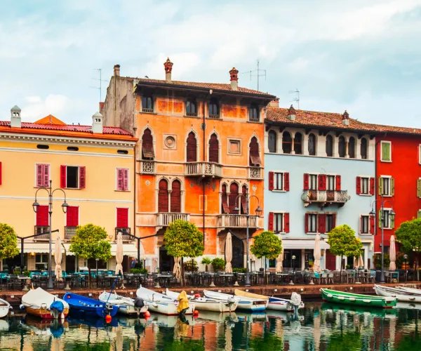 Colorful buildings and boats line a canal under a cloudy sky.