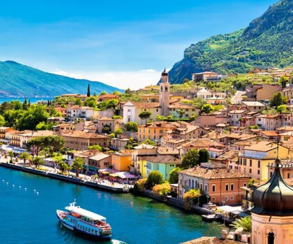 Colorful coastal town with mountains and a blue lake.