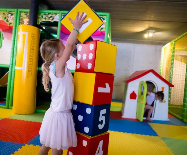 Child stacking colorful numbered blocks in a playroom.