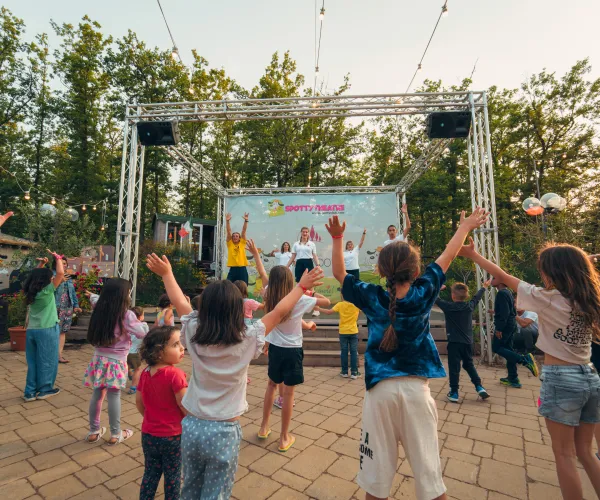 Children dancing joyfully at an outdoor event under string lights.