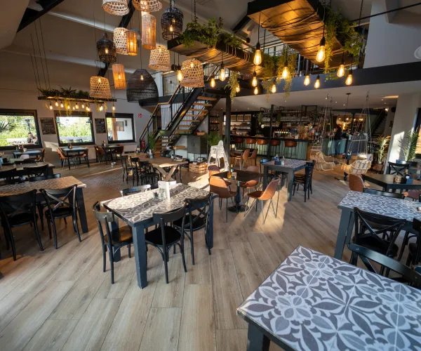 Spacious, modern restaurant with wooden floors and hanging lights.
