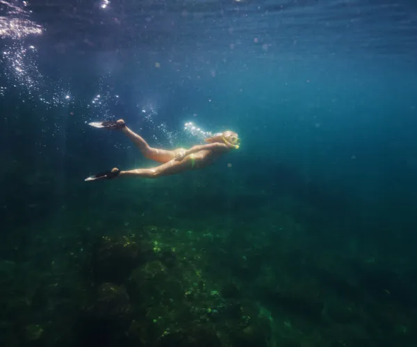 A person snorkeling underwater in clear blue water.